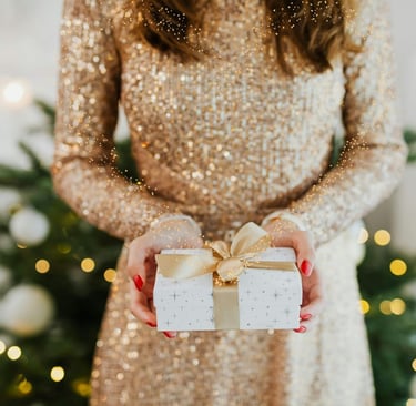 a woman holding a present box with a gold bow