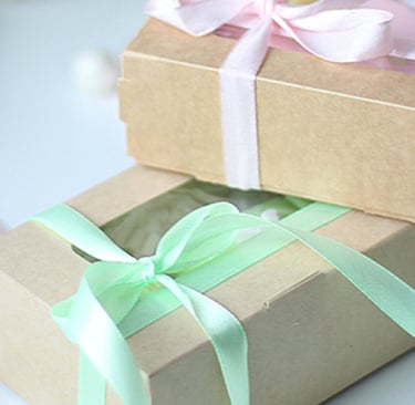 a pair of boxes with a pink ribbon tied to them