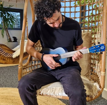a man sitting on a swing chair with a guitar