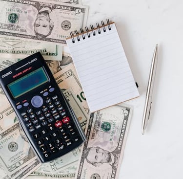 calculator, money, pen, and paper representing making a budget and overall planning finances