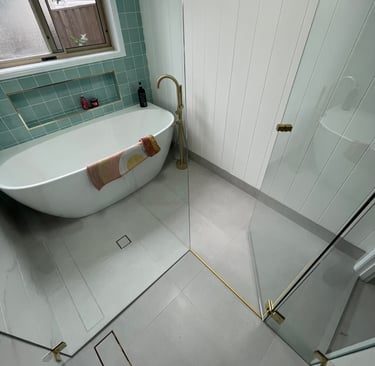 Frameless shower screen enclosure with brushed brass hardware