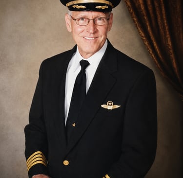 Formal portrait of Captain Art Rainbolt wearing an airline pilot’s uniform and captain’s hat. 