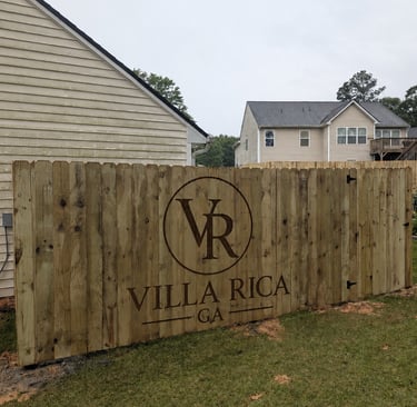 Custom wood privacy fence in Villa Rica GA featuring a laser engraved logo and residential neighborhood view.