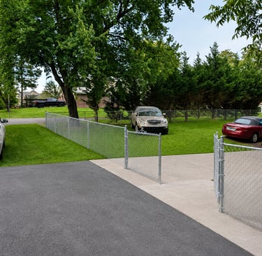 Galvanized silver chain link fence installed along a residential driveway and green lawn.