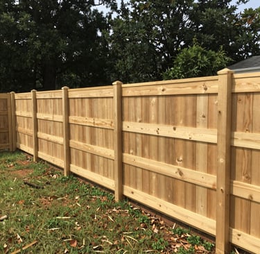New wooden privacy fence with vertical cedar pickets and sturdy posts installed in a backyard.