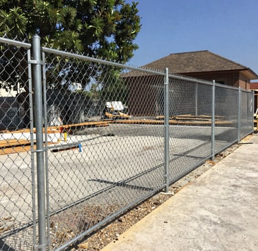 Galvanized steel chain link fence installed at a residential construction site for security.