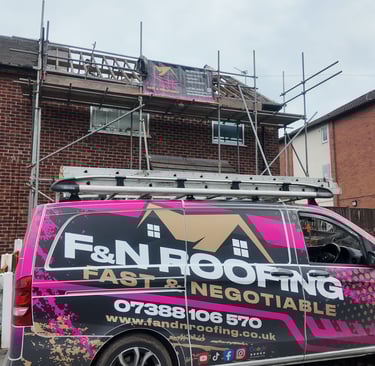 Professional roofing contractors repairing a brick house roof with scaffolding and a branded F&N Roofing van.