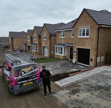 Professional roofing contractor van parked in front of a new build housing development under construction.