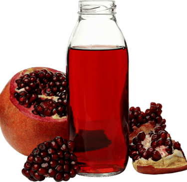 une bouteille de jus de grenade et des grenades fraîches.