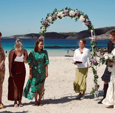 a group of people standing on a beach for a wedding