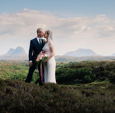 a bride and groom standing on a hill top