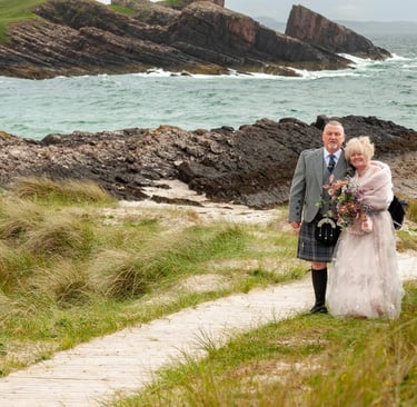 a bride and groom walking down a path on a beach