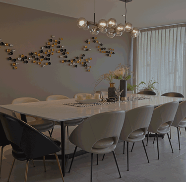 Comedor amplio con mesa de mármol, sillas curvas beige y decoración mural artística | KARÄNA