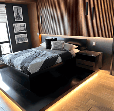 Recámara de lujo con iluminación LED en plataforma, muro de madera y cama en negro mate | KARÄNA