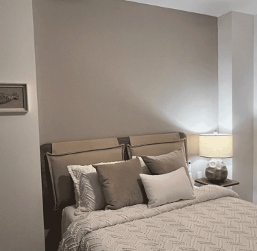 Recámara con cama tapizada, iluminación cálida y paleta de colores neutros en interiorismo acogedor
