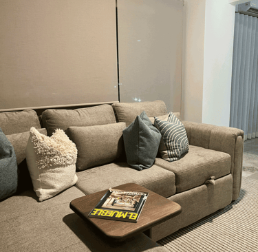 Sala con sofá seccional en tonos tierra, cojines decorativos y mesa auxiliar de madera | KARÄNA