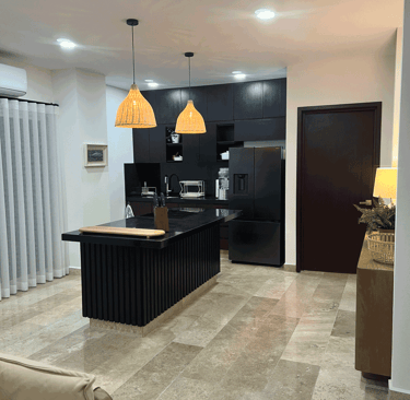 Diseño contemporáneo en cocina con isla central, iluminación cálida y acabados en negro | KARÄNA