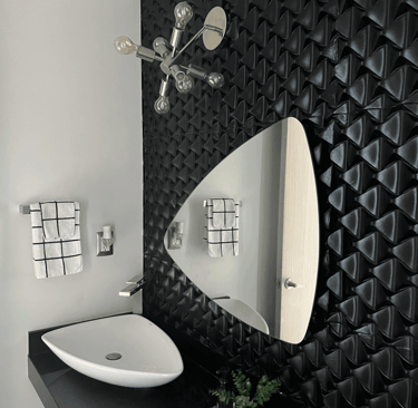 Baño moderno con lavabo blanco, muro tridimensional negro y espejo orgánico, interiorismo | KARÄNA