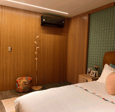 Recámara con cabecera de terciopelo color miel, muro verde acolchado y detalles en madera | KARÄNA.
