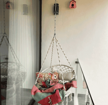 Balcón con columpio de cuerda, cojines decorativos y manta colorida, estilo bohemio | KARÄNA