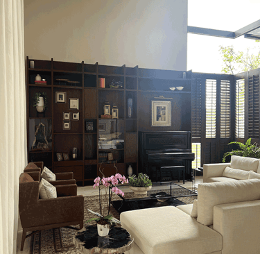 Sala elegante con estantería de madera y piano vertical al fondo | KARÄNA