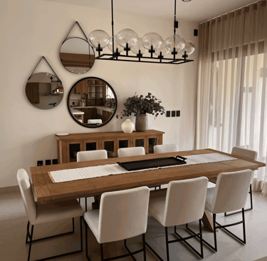 Comedor con mesa de madera, sillas blancas, cortinas y conjunto decorativo de espejos | KARÄNA