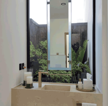 Lavabo minimalista con espejo suspendido y jardín interior | KARÄNA