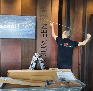 JustSignage, a man is hanging a display