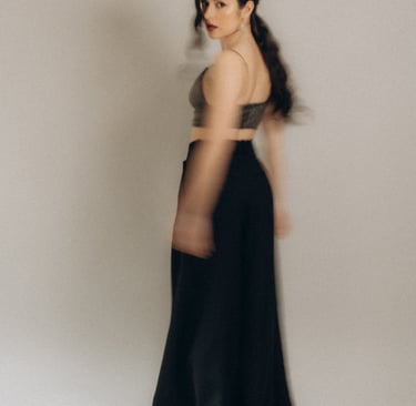 a woman in a black dress standing in front of a white wall