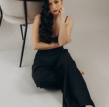 a woman sitting on a chair with her hand on her chin
