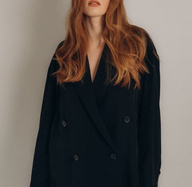 a woman with long and orange hair in a black coat.