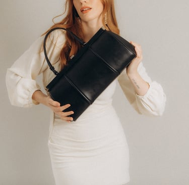 a woman in a white dress and a black purse