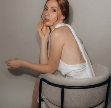 a woman in a white dress sitting on a chair