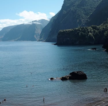Black sand beach at Praia do Porto do Seixal with cliffs and calm sea