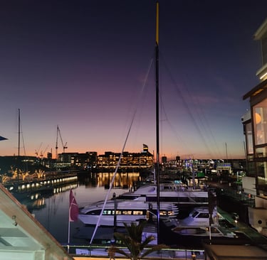 Viaduct Marina, Auckland, New Zealand. View of sunset, city lights and moored yachts