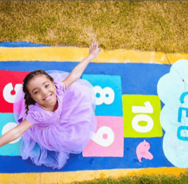 Criança sentada em cima de uma amarelinha. foto de cima (aerea)