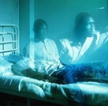 two people sitting on a bed in a hospital room