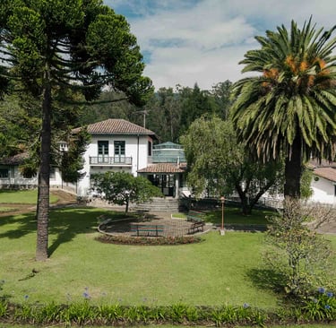 Fotografía con dron de mansión colonial de paredes blancas con techo naranja, cúpulas rodeada de naturaleza Quito Ecuador