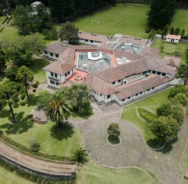 Fotografía con dron de mansión colonial de paredes blancas con techo naranja, cúpulas rodeada de naturaleza Quito Ecuador