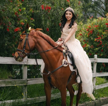 Fotografía de quinceañera con vestido amarillo montada a caballo en un lugar con vallas, flores rojas de Quito Ecuador