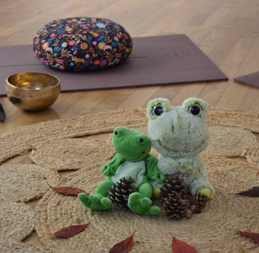 deux peluches grenouille sur un tapis avec un bol de meditation et des coussins de méditation
