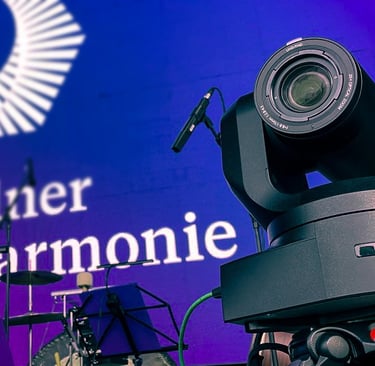 Professionelle Videokamera auf Bühne mit Giesinger Harmonie-Logo.