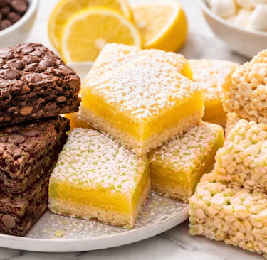 Assorted dessert platter with chocolate chip brownies, powdered lemon bars, and rice cereal treats.