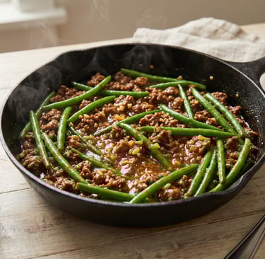Sizzling ground beef and green bean stir fry in a cast iron skillet with white rice.