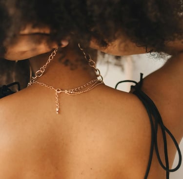 a woman with a black bralet and a gold chain link necklace