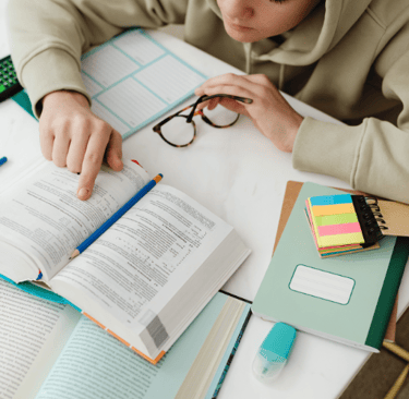 une étudiante sage-femme étant assise avec un livre et des lunettes