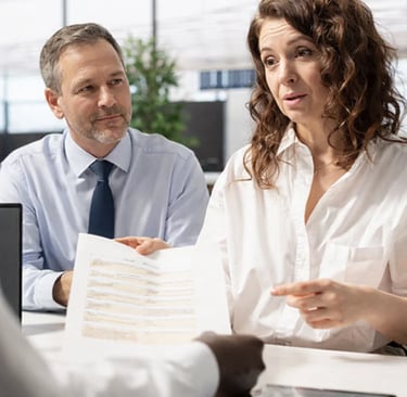Professional business consultants reviewing legal documents and contracts with a client in a modern office.