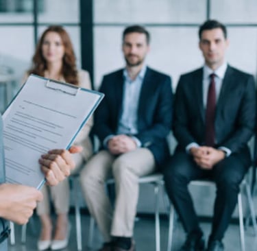 HR manager holding a clipboard while interviewing a panel of professional job candidates.
