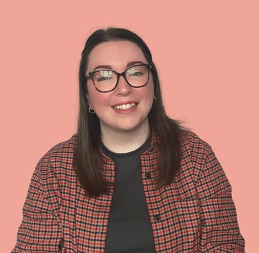 A women (Erin, owner of EB Socials) with brown hair, glasses and an orange checked shirt, smiling at the camera