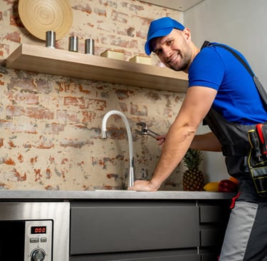 Plombier souriant utilisant une clé pour réparer un robinet de cuisine et inspecter prévenir urgence